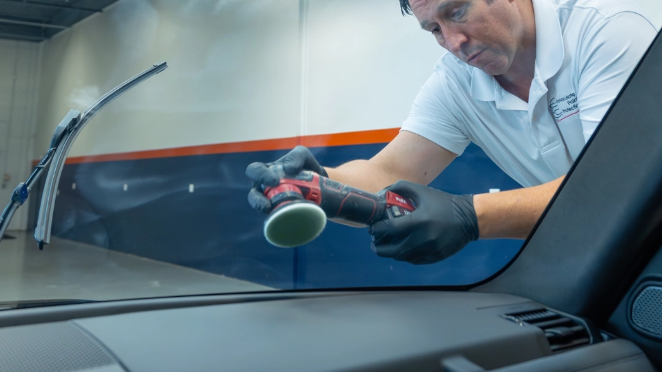 View from inside a 2024 Land Rover Defender looking out as Bill machine polishes the windshield. This critical prep step ensures the ceramic glass coating bonds perfectly, creating a hydrophobic barrier that instantly repels rain and snow for safer driving in any vehicle.