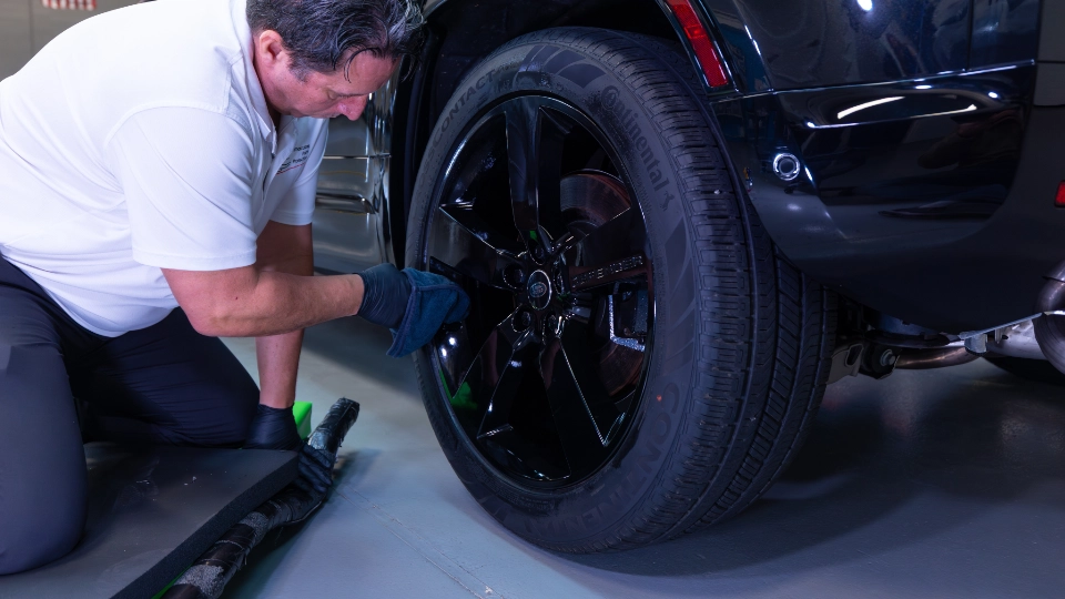 Detail of a professional ceramic wheel coating application on a 2024 Land Rover Defender alloy rim. This high-temperature protection prevents brake dust pitting and road salt corrosion, making wheels on any car or truck effortless to clean.